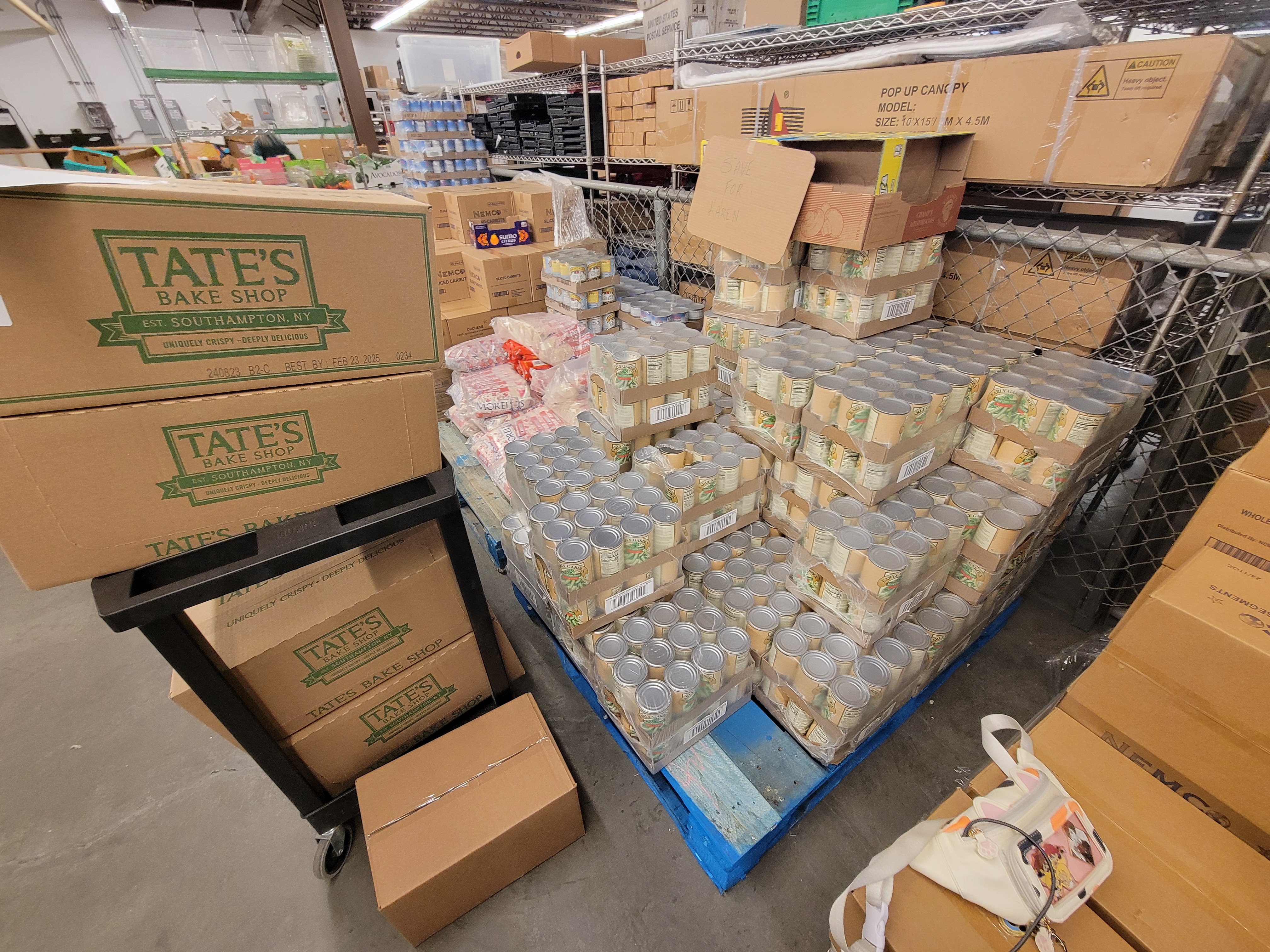 Pallets of food next to shelf cart full of boxes of lemon cookies.